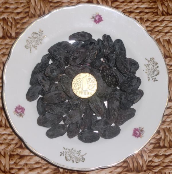 Высушенные ягоды винограда на фарфоровой тарелке и монетка посередине