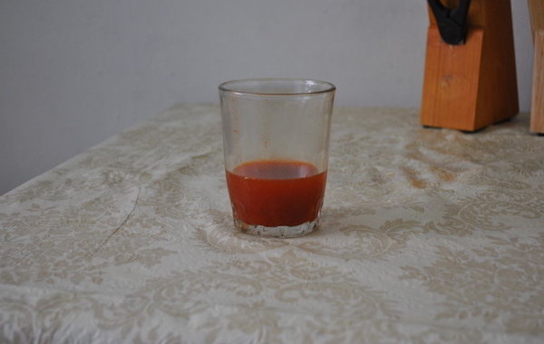 Стеклянный стакан с раствором острого перца на кухонном столе
