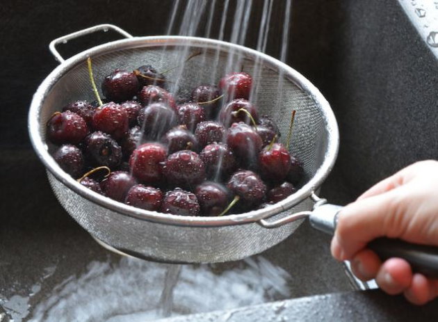 Промывание спелых плодов вишни через дуршлаг перед заморозкой